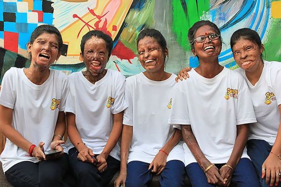 the staff of Sheroes Hangout in Agra, India, sit in front of mural